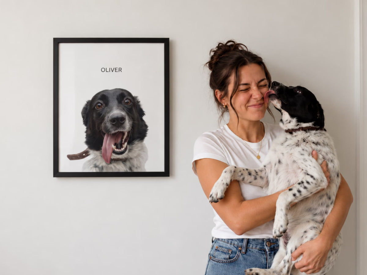 A portrait with the name 'Oliver' hanging on a white wall with the dog mom holding the same dog Oliver in her arms licking her face