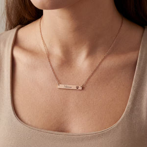 Rose gold necklace with engraved name on a person wearing a beige top