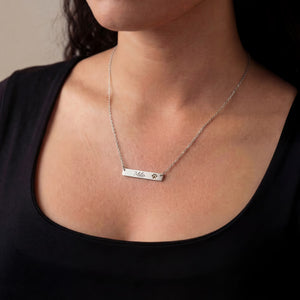 Silver necklace with engraved name on a person wearing a black top